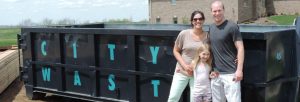 family in front of dumpster